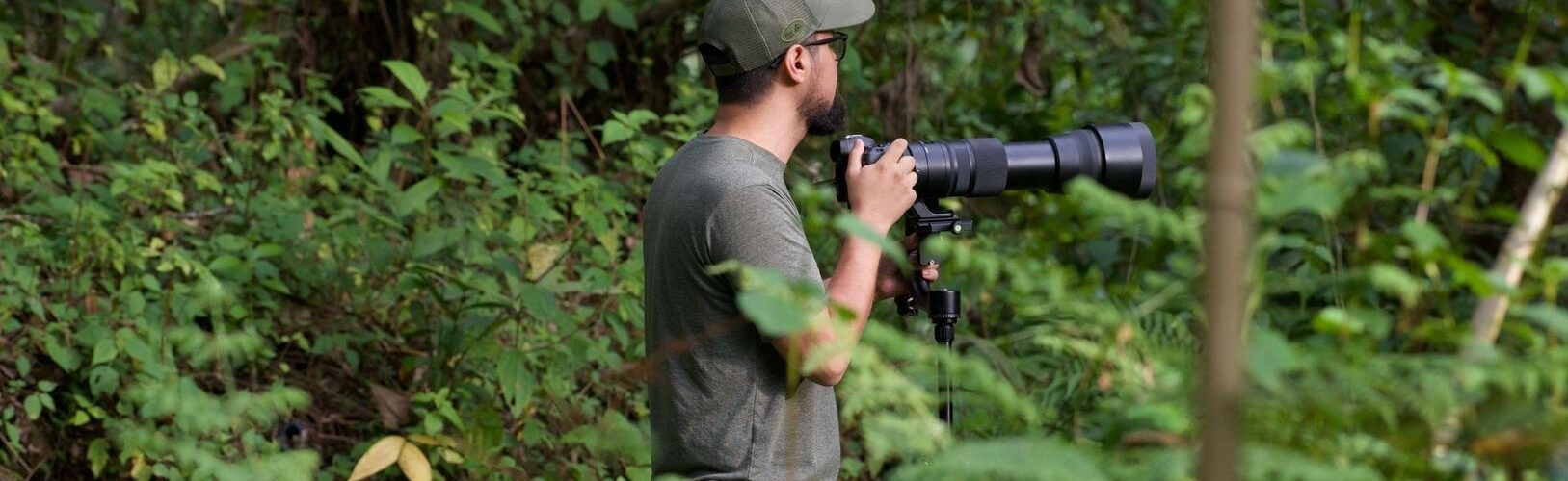 Naturfotograf mit langem Teleobjektiv im dichten Wald